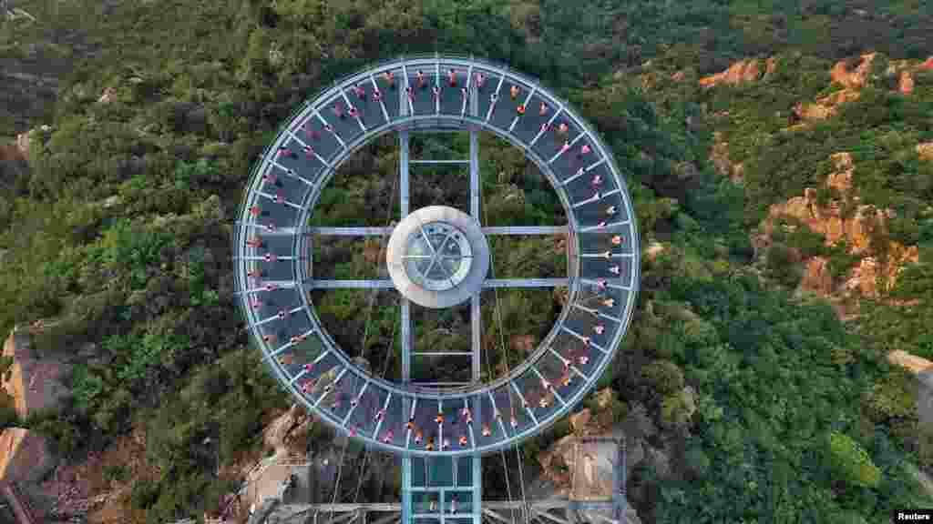 An aerial view shows people practicing yoga on a glass sightseeing platform ahead of the International Day of Yoga, on the outskirts of Beijing, China.