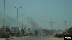 Un tanque se quema a la distancia tras ser impactado por un ataque aéreo en Tripoli, Libia.