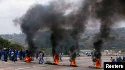 Wafuasi wa Rais wa zamani wa Afrika Kusini Jacob Zuma wakichoma matairi kuzuia magari kupita wakati wa maandamano huko Peacevale, Afrika Kusini, Julai 9, 2021.