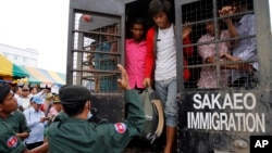 Cambodian migrant workers get off from a Thai truck upon their arrival from Thailand at Cambodia-Thai international border gate in Poipet, Cambodia, Tuesday, June 17, 2014.