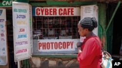 A pedestrian walks past an internet cafe in the low-income Kibera neighborhood of Nairobi, Kenya Wednesday, Sept. 29, 2021. (AP Photo/Brian Inganga)