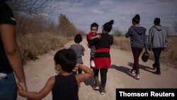 Inmigrantes atraviesan un camino de tierra después de cruzar el Río Grande, en la frontera de Estados Unidos con México en Penitas, Texas, a inicios de marzo de 2021. 