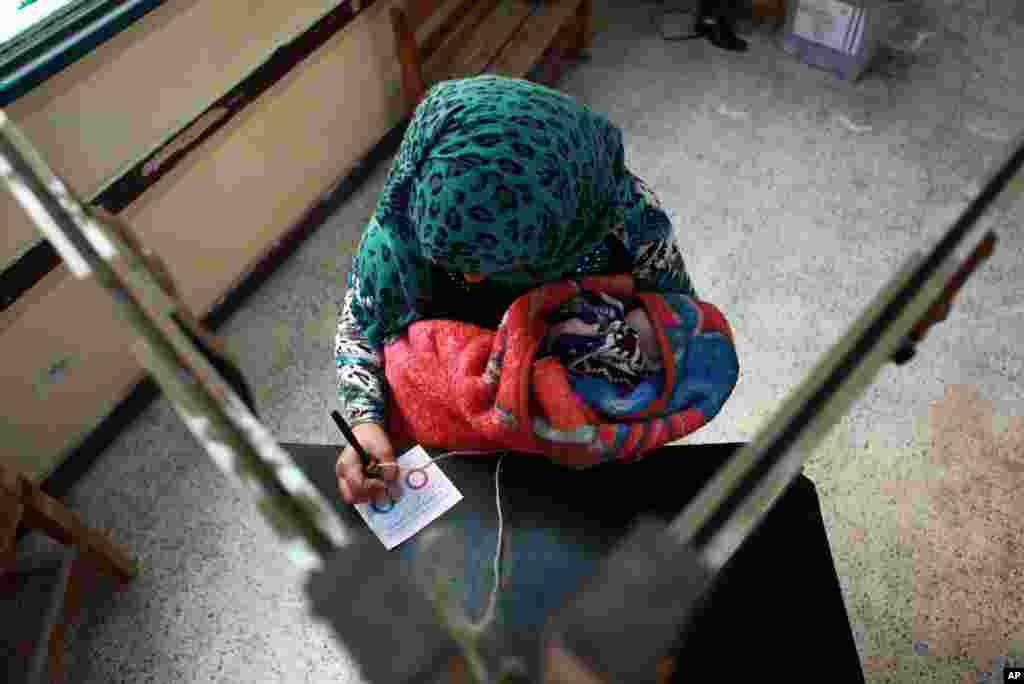 A woman holds a child as she casts her vote in the country's constitutional referendum in Hawamdaya, south of Cairo, Jan. 14, 2014. 