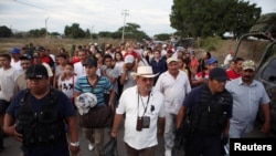 ARCHIVO - Hipólito Mora y otros vigilantes caminan con su familia y amigos para cooperar voluntariamente en la investigación de un tiroteo en La Ruana, Michoacán, el 27 de diciembre de 2014.