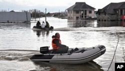 به دنبال شکستن بخشی از سد در اورسک روسیه و طغیان رودخانه‌های اطراف، مردم با قایق‌های لاستیکی در خیابان‌های سیل زده حرکت می‌کنند. اورسک، روسیه، ۲۱ فروردین ۱۴۰۳ 
