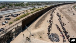 Migrantes forman filas frente a la valla en la frontera de Estados Unidos con México a la espera de ser transportados a una instalación de la Patrulla Fronteriza, el 10 de mayo de 2023, en El Paso, Texas.