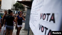 ARCHIVO - La gente mira dónde tienen que votar en una primaria para elegir un candidato de la oposición para enfrentar al presidente de Venezuela, Nicolás Maduro, en su probable candidatura a la reelección en 2024, en Caracas, el 22 de octubre de 2023. 