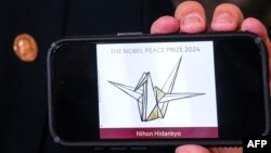 一部手機螢幕顯示2024年諾貝爾和平獎得主--日本組織Nihon Hidankyo的標識。
