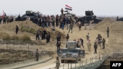 Lực lượng an ninh Iraq tập trung gần một cây cầu tạm được xây dựng bởi các kỹ sư quân đội Iraq ở phía nam Ramadi, trong chuyến thăm của Thủ tướng Iraq Haider al-Abadi ngày 29 tháng 12 năm 2015, sau khi lực lượng chính phủ chiếm lại thành phố từ Nhà nước Hồi giáo.