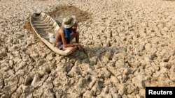  រូបឯកសារ៖ បុរសម្នាក់អង្គុយលើទូកនេសាទដែលជាប់ក្នុងបឹងដែលស្ងួតហួតហែង ដោយសារគ្រោះរាំងស្ងួត នៅខេត្តកណ្តាល ប្រទេសកម្ពុជា កាលពីថ្ងៃទី​១៣ ខែឧសភា ឆ្នាំ២០១៦។