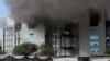 Employees leave as smoke rises from a fire at Serum Institute of India, the world's largest vaccine maker that is manufacturing the AstraZeneca/Oxford University vaccine for the coronavirus, in Pune, Jan. 21, 2021.