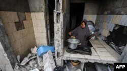 Mwanamke wa Kipalestina aliyerejea katika makazi yake yaliyopigwa bomu na Israeli akipika chakula, baada ya kusitishwa mapigano kati ya Israeli na Hamas yaliyosimamiwa na Misri (Photo by MOHAMMED ABED / AFP)