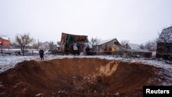 Un residente local se encuentra junto a un cráter en el lugar de un ataque con misiles rusos, en medio del ataque de Rusia a Ucrania, en Kiev, Ucrania, el 11 de diciembre de 2023. [Foto: Reuters]