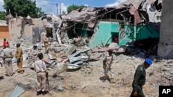 Somali soldiers look at the destroyed houses amidst the wreckage of a car bomb blast in Mogadishu, Somalia, May 17, 2017. Three bomb disposal experts were killed as they were trying to dismantle the car laden with explosives, according to police.