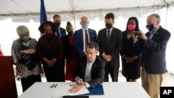 Guverner Virdžinije Ralf Nortam, okružen zakonodavcima i aktivistima, potpisuje zakon o ukidanju smrtne kazne u toj državi, u Kazneno-popravnom centru u Džaratu, Virdžinija, 24. marta 2020.