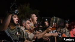 Security forces charge demonstrators after being hit by water bottles during a protest against the shooting of unarmed black teen Michael Brown in Ferguson, Missouri Aug. 20, 2014.