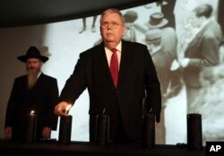 FILE - U.S. Ambassador to Russia John Tefft lights a candle at a ceremony marking the International Holocaust Remembrance Day in the Jewish Museum and Tolerance Center in Moscow, Russia, Jan. 27, 2017. At left is Russia's chief rabbi, Berel Lazar.