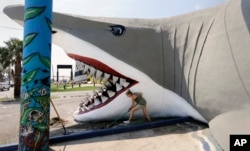 Olya Soya works to clear debris from the beach shop, Destinations, in Port Aransas, Texas, Sept. 29, 2017.