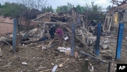 Un oficial de policía ucraniano ayuda a una residente local a dejar su casa arruinada en el mortal ataque matutino con cohetes rusos en Kostyantynivka, región de Donetsk, Ucrania, el miércoles 14 de junio de 2023.