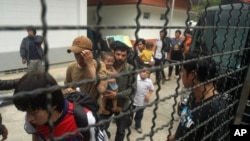 2014年3月15日，逃到泰國的維吾爾穆斯林在一輛警車旁站隊。