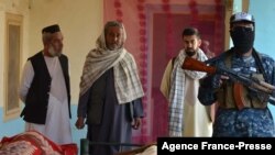 Talibanski borac, desno, uz civile stoji uz telo ubijenog u operacijama talibana protiv pripadnika Islamske države Horasana, lokalnog ogranka IS, u Kandaharu, 15. novembra 2021.