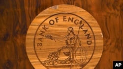 A wooden carving of the Bank of England logo is seen on a desk during a news conference by Bank of England governor Mark Carney at the Bank of England in London, Britain July 5, 2016. Carney says some of the risks predicted to the economy before the…