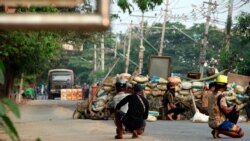 Anti-coup protesters squat behind a barricade that separates them from security forces on the opposite side of the road, in the Dala township of Yangon, Myanmar, Mar. 26, 2021.