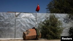 新疆乌鲁木齐外昌吉市一所清真寺被拆掉的尖塔残骸的一部分与中国国旗。 （2021年5月6日）