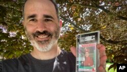 الی تارانتینو با کارت بیسبالی با تصویر مارک زاکربرگ در سن دبستان