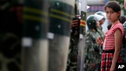 2009年7月9日一維吾爾族女孩在新疆省烏魯木齊觀看遊行被防暴警察攔住。