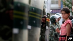 烏魯木齊一位維吾爾族女孩站在一排防爆警察面前。（資料照）