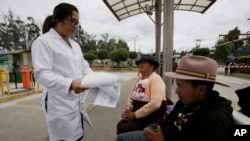Una doctora del Ministerio de Salud habla con la gente en la estación de autobuses donde les entrega información escrita sobre el coronavirus en Quito, Ecuador.