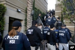 FILE - Federal agents enter an upscale apartment complex, Tuesday, March 3, 2015, in Irvine, Calif. Shortly after sunrise, federal agents swarmed the complex in the Orange County where authorities say a birth tourism business charged pregnant women $50,000