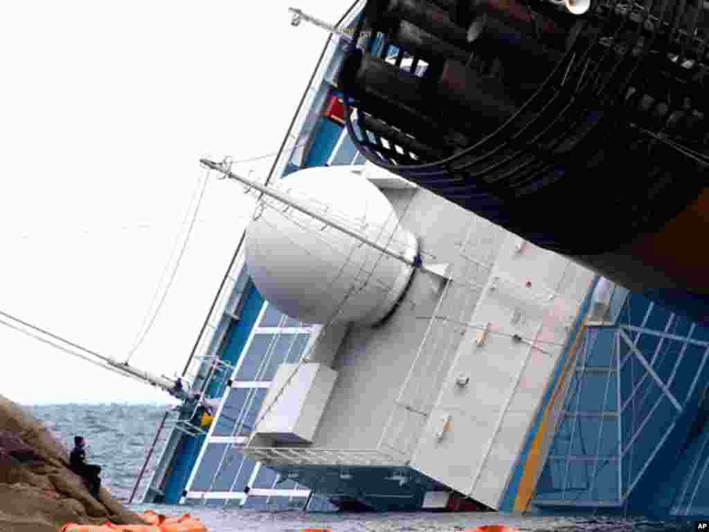 A scuba diver rests on the rocks on January 18, 2012 as he looks at the Costa Concordia cruise ship that ran aground off the west coast of Italy, at Giglio island. (Reuters)