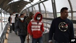 Central American migrants seeking asylum, some wearing protective face masks, return to Mexico via the international bridge at the U.S-Mexico border that joins Ciudad Juarez and El Paso, Saturday, March 21, 2020.