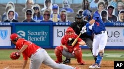 Los Angeles Dodgers' Chris Taylor, right, hits a three-run home run against Los Angeles Angels pitcher Jaime Barria, left, during the third inning of a preseason baseball game July 21, 2020. In the stand are cut-outs of baseball fans. (AP Photo/Mark J. Terrill)
