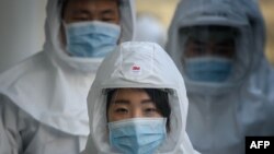 រូបឯកសារ៖ បុគ្គលិក​សុខាភិបាល​ពាក់​ម៉ាស​និង​សម្លៀក​បំពាក់​ការពារ​ការ​ឆ្លង​ជំងឺកូវីដ១៩ កំពុង​ដើរ​នៅ​សាកល​វិទ្យាល័យ Keimyung ក្រុង Daegu ប្រទេស​កូរ៉េ​ខាង​ត្បូង កាល​ពី​ថ្ងៃ​ទី​១២​ មីនា ២០២០។