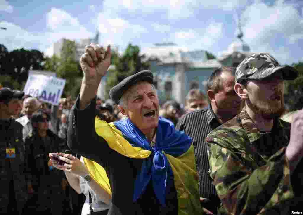 People take part in a rally to press demands for parliament to be dissolved and early elections outside the assembly in Kyiv, June 17, 2014. 