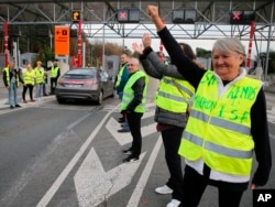 A demonstrator wearing a yellow jacket reading "Macron give us the wealth tax" protests at the toll gates on a motorway at Biarritz southwestern France, Dec. 5, 2018.