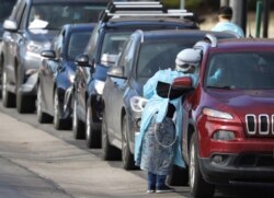 Health care workers test people at a drive-thru testing station run by the state health department, for people who suspect they have novel coronavirus, in Denver, Colorado, March 11, 2020.