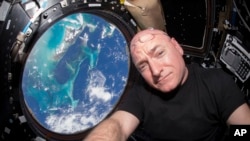 In this July 12, 2015 photo, Astronaut Scott Kelly takes a photo of himself inside the Cupola, a special module of the International Space Station that provides 360-degree viewing of the Earth and the station.