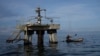 ARCHIVO - Un pescador navega cerca de una instalación petrolera en el Lago de Maracaibo, en el occidente de Venezuela, el 12 de octubre de 2022.