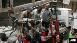 Syrian civil defense volunteers, known as the White Helmets, pass the body of a boy after he was pulled from the rubble following a government forces airstrike on the rebel-held al-Shaer neighborhood of Aleppo, Sept. 27, 2016.