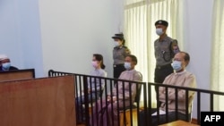This handout photo taken on May 24, 2021 and released by Myanmar's Ministry of Information on May 26 shows detained civilian leader Aung San Suu Kyi (L) and detained president Win Myint (C) during their first court appearance in Naypyidaw, since the military detained them in a co