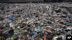 A man walks on the shores the Arabian Sea, littered with plastic and other garbage in Mumbai, India, Monday, June 4, 2018. The theme for this year's World Environment Day, marked on June 5, is "Beat Plastic Pollution." (AP Photo/Rafiq Maqbool)