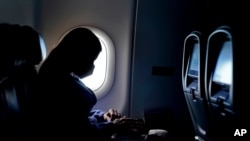 FILE - In this Feb. 3, 2021 file photo, a passenger wears a face mask during an airline flight after taking off from Atlanta.