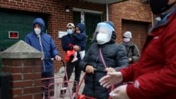 Antonio Sanchez holds his 2-year-old daughter, Kyle, as they wait in line for food at the United Sherpa Association's weekly food pantry on Friday, January 15, 2021. (AP Photo/Jessie Wardarski)