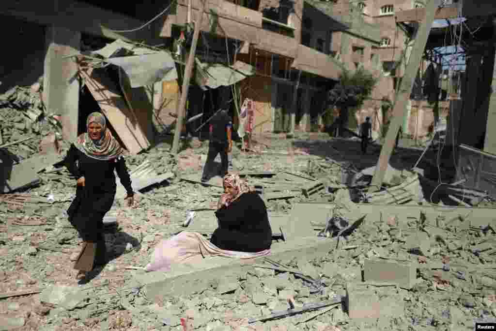 Falastinlik ayol G'azodagi vayron bo'lgan uyi xarobalari ustida o'tiribdi, G'azo, 26-iyul, 2014-yil.