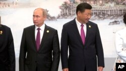 Russian President Vladimir Putin, left, and Chinese President Xi Jinping line up for a photo during the BRICS Summit in southeastern China's Fujian province, Sept. 4, 2017.