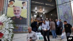 Ljudi napuštaju džamiju u dominantno iračkom južnom kraju Teherana, 30. jula 2019. Na zidu se vidi poster sa likom generala Kasema Sulejmanija, zajedno sa vrhovnim liderom Ali Hameneijem i ajatolom Homeinijem.